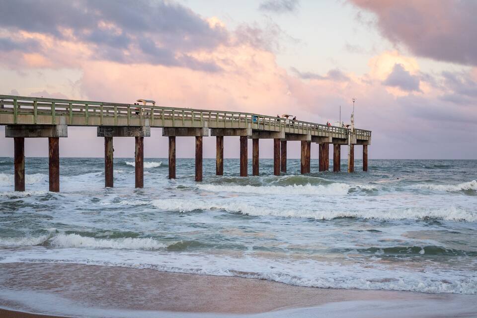 A pier extending into the ocean with waves crashing against it.