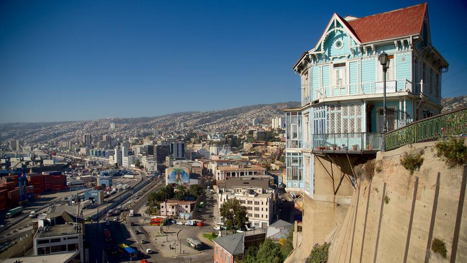 A coastal cityscape with a prominent blue building with a balcony overlooking the harbor.