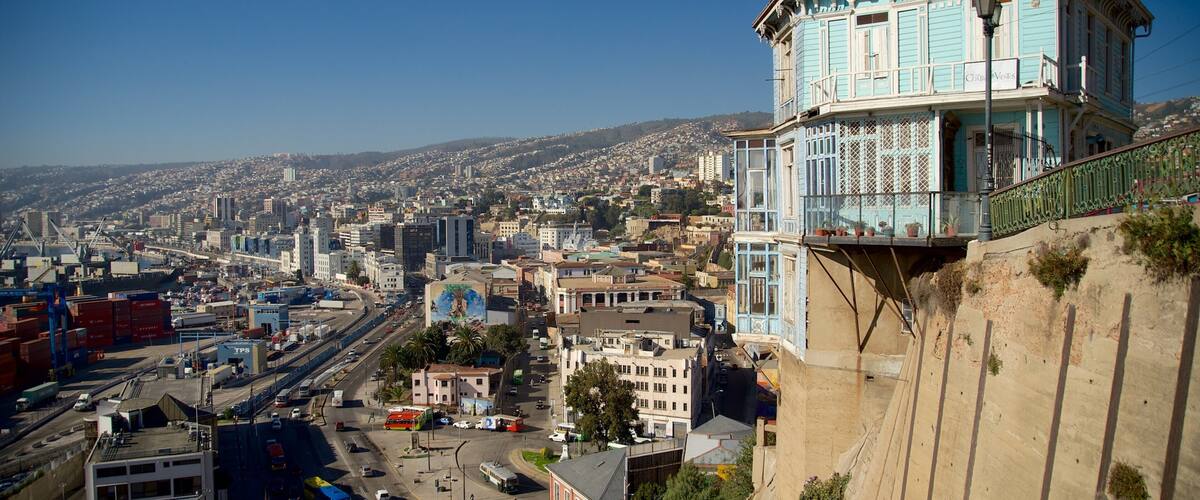 A coastal cityscape with a prominent blue building with a balcony overlooking the harbor.