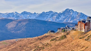 A mountainous landscape with snow-capped peaks and a cluster of traditional buildings on a hillside.