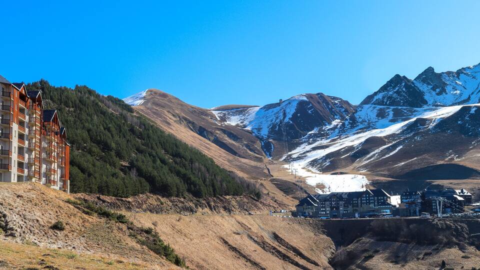 A mountainous landscape with a ski resort, a lodge, and a building with balconies.