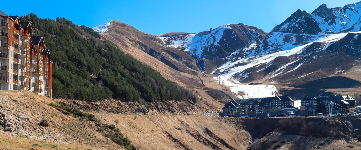 A mountainous landscape with a ski resort, a lodge, and a building with balconies.
