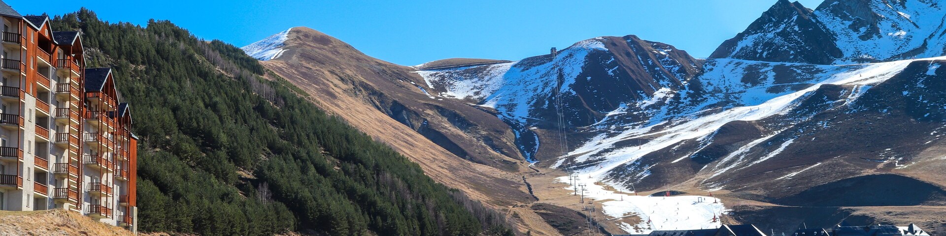 A mountainous landscape with a ski resort, a lodge, and a building with balconies.