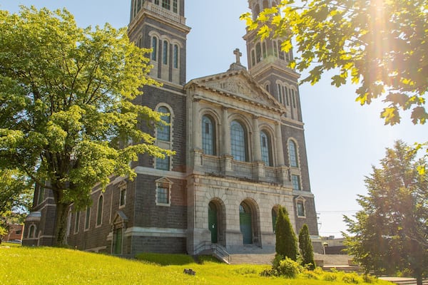 Une église historique dotée de deux tours, entourée d’arbres et d’herbe verdoyants.