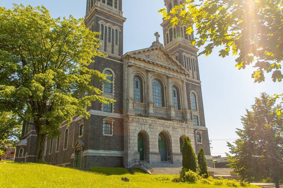 A historic church with two towers, surrounded by lush green trees and grass.