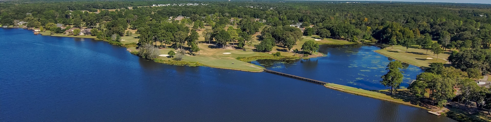 an aerial shot of a gorgeous autumn landscape on Houston Lake with rippling blue water surrounded by lush green trees, grass and plants and homes with a gorgeous clear blue sky in Perry Georgia USA
