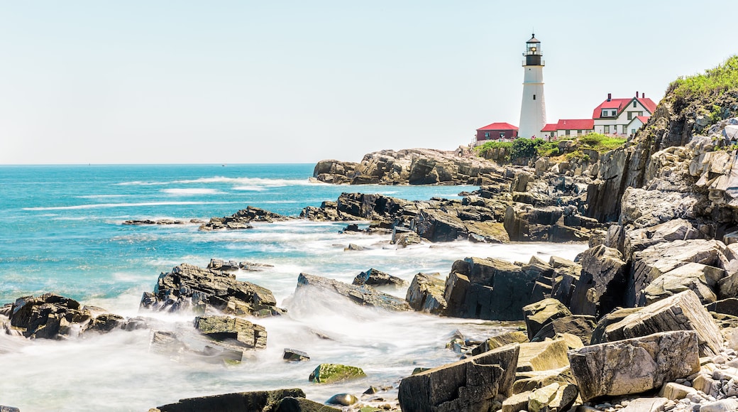 Cliff rocks side view shore with Portland Head Lighthouse in Fort Williams park in Cape Elizabeth, Maine during summer day