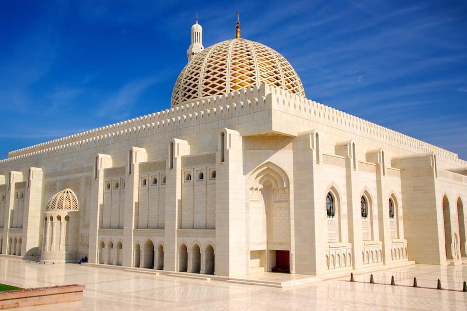 Uma grande mesquita branca com uma cúpula dourada e janelas em arco.