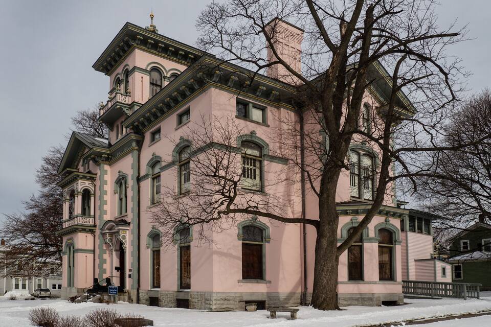 A large pink building with green trim and a large tree in front.