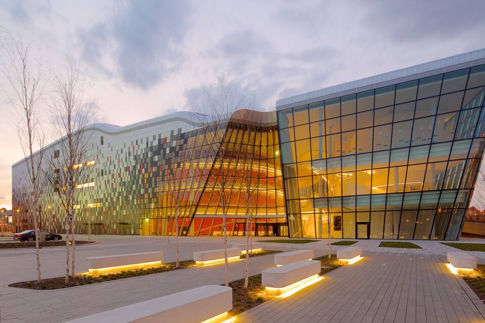 A modern building with a reflective glass facade and a unique curved design.
