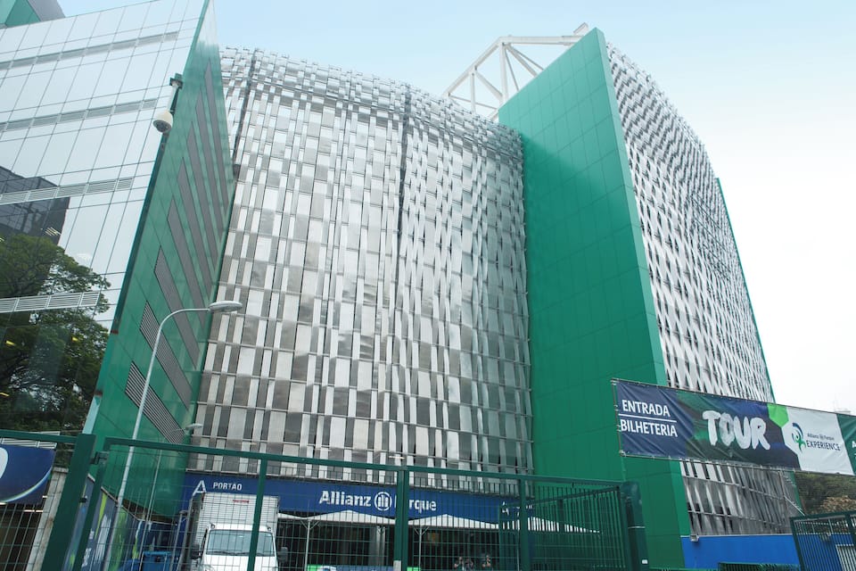 A modern building with a reflective glass facade and a prominent green structure to its right.