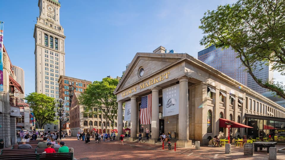 A historic building with "QUINCY MARKET" sign, surrounded by modern buildings and a clock tower.