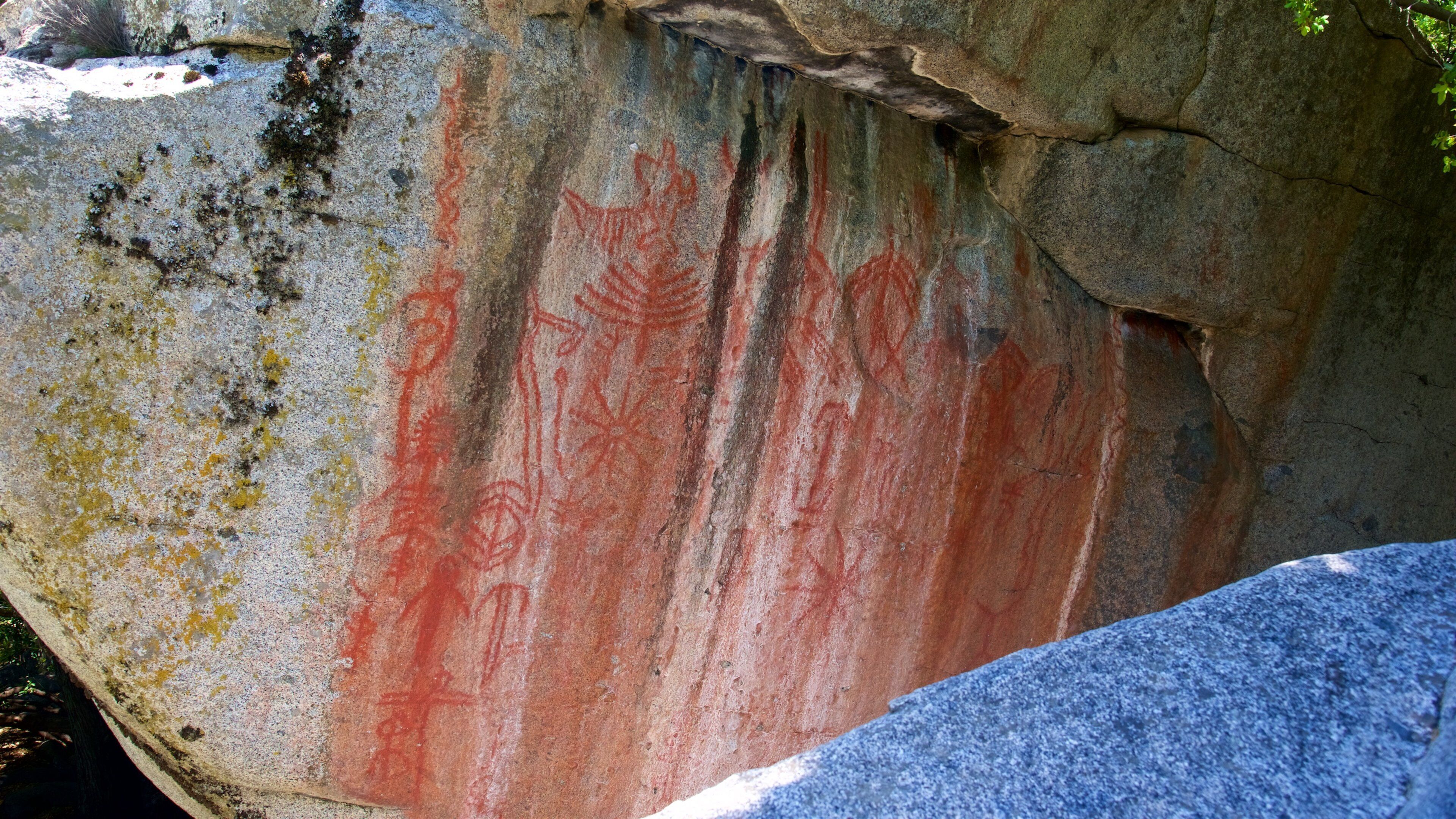 A large rock with red and yellow markings, likely ancient petroglyphs.