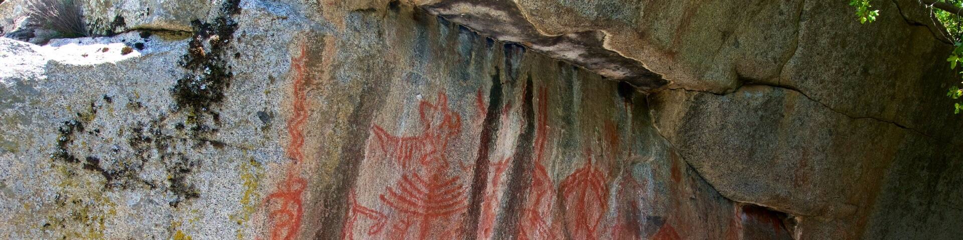 A large rock with red and yellow markings, likely ancient petroglyphs.