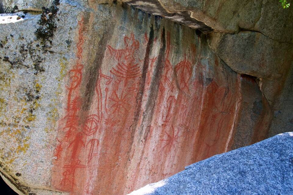 A large rock with red and yellow markings, likely ancient petroglyphs.