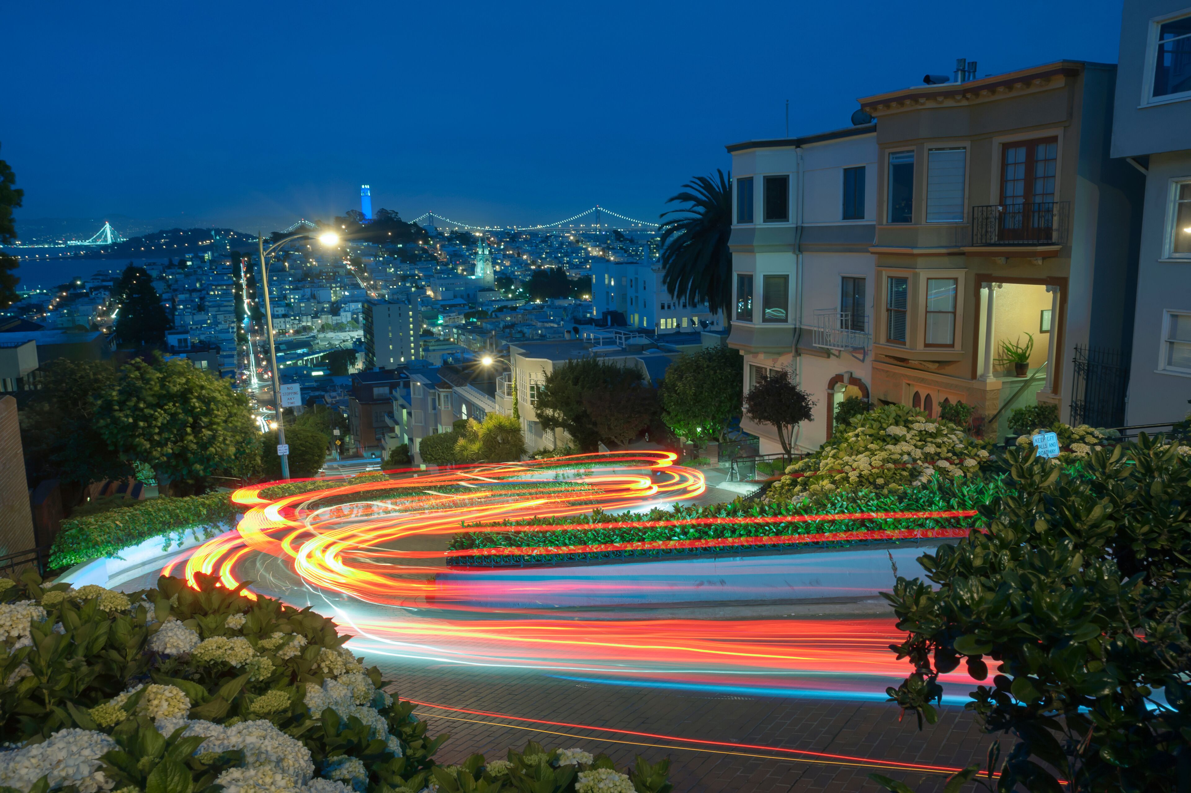 A nighttime cityscape with illuminated streets, a bridge, and residential buildings.