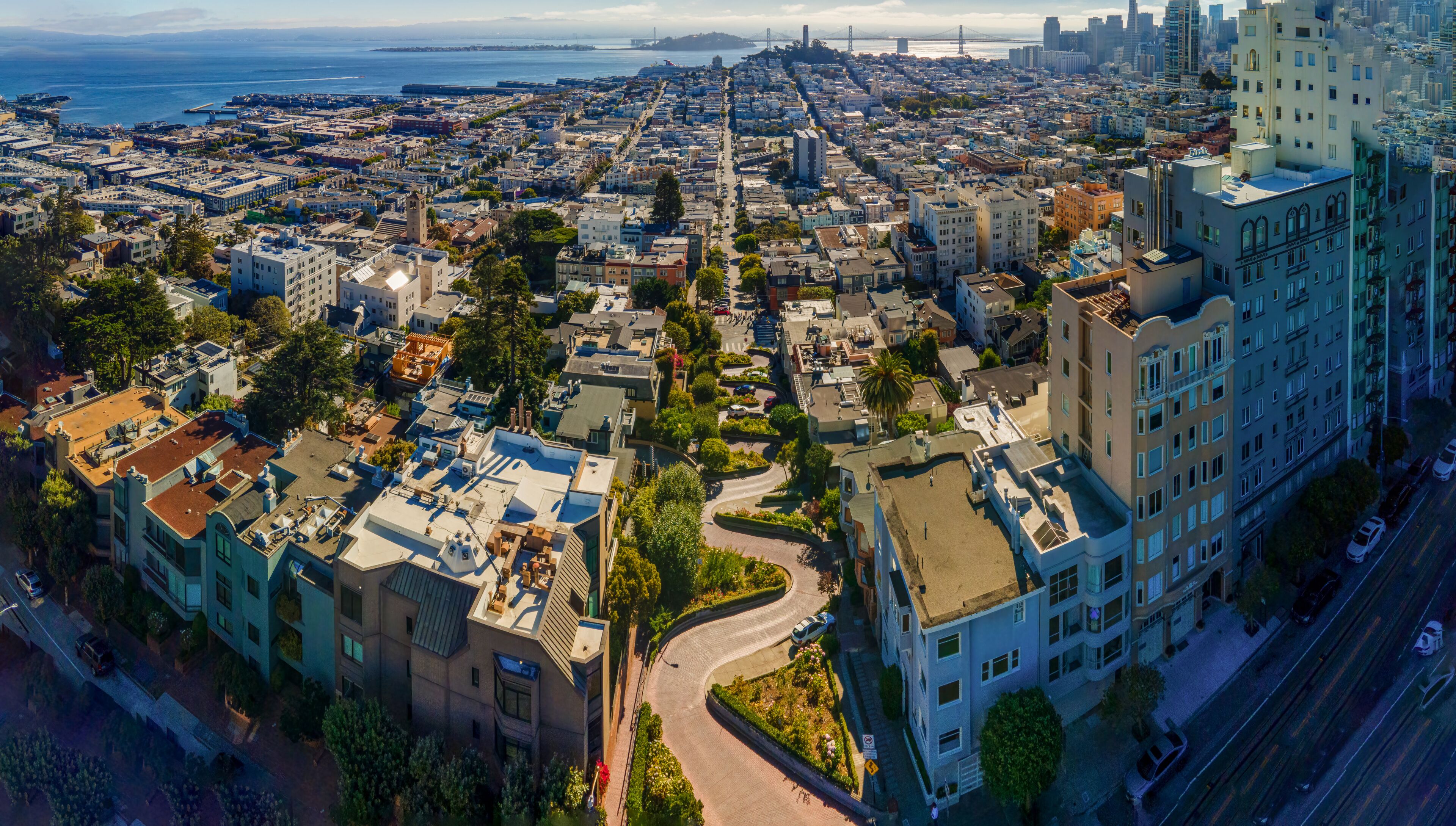 A cityscape with a prominent bridge, dense urban buildings, and a coastline.