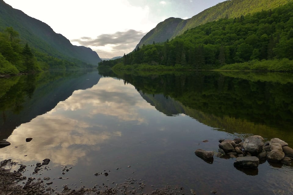 A calm lake surrounded by forested hills.