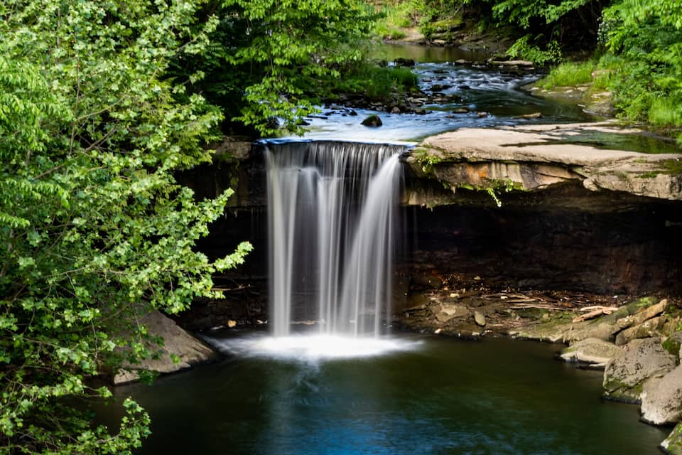 A waterfall in a forested area with a clear stream below.
