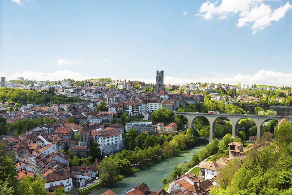 Un río fluye por una ciudad con edificios históricos y una imponente torre de iglesia.