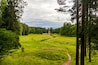 Summer landscape in a city Park with trees, a tower with a stone bridge, sky with clouds