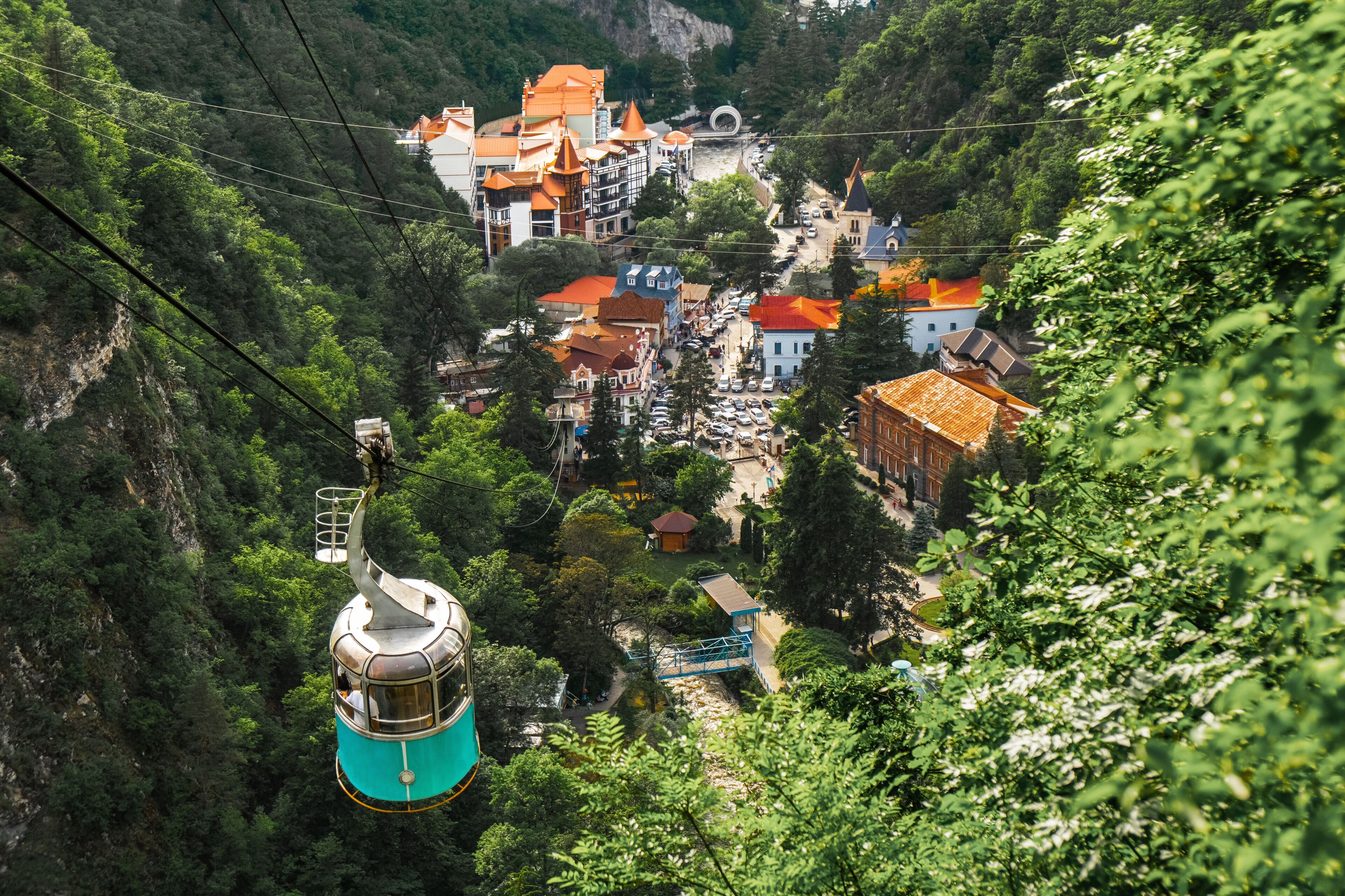 A cable car system in a mountainous area with buildings and greenery.