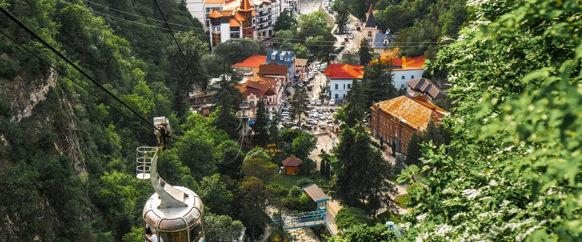 A cable car system in a mountainous area with buildings and greenery.