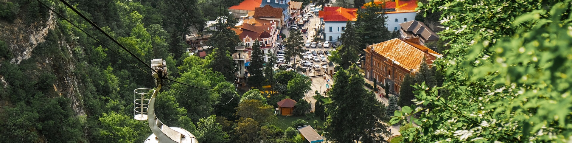A cable car system in a mountainous area with buildings and greenery.