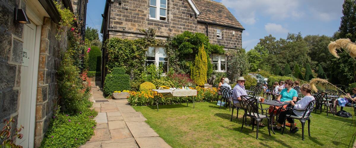A stone building with a garden and outdoor seating.