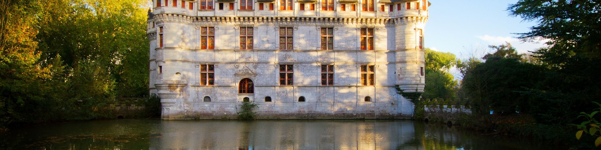 A historic castle with multiple towers, a moat, and a reflection in the water.