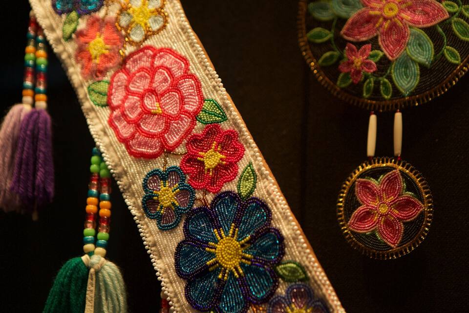 Primer plano de un tejido con cuentas y bordados florales de colores.