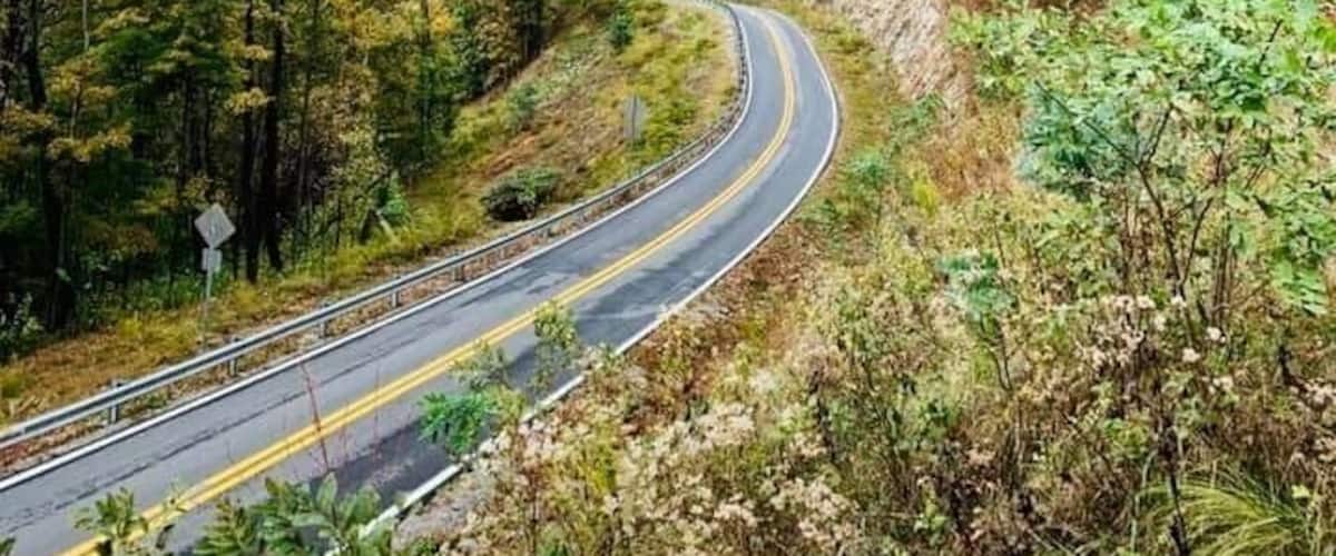 A winding road through a forested area with autumn foliage.