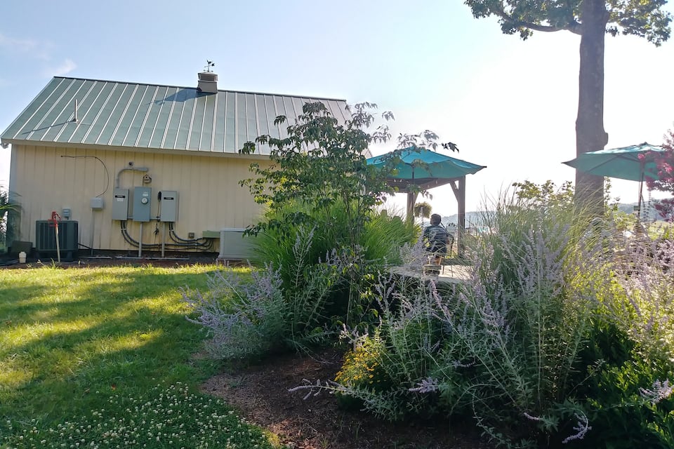 Ein Gebäude mit einem begrünten Dach, umgeben von einem Garten mit verschiedenen Pflanzen und Blumen.