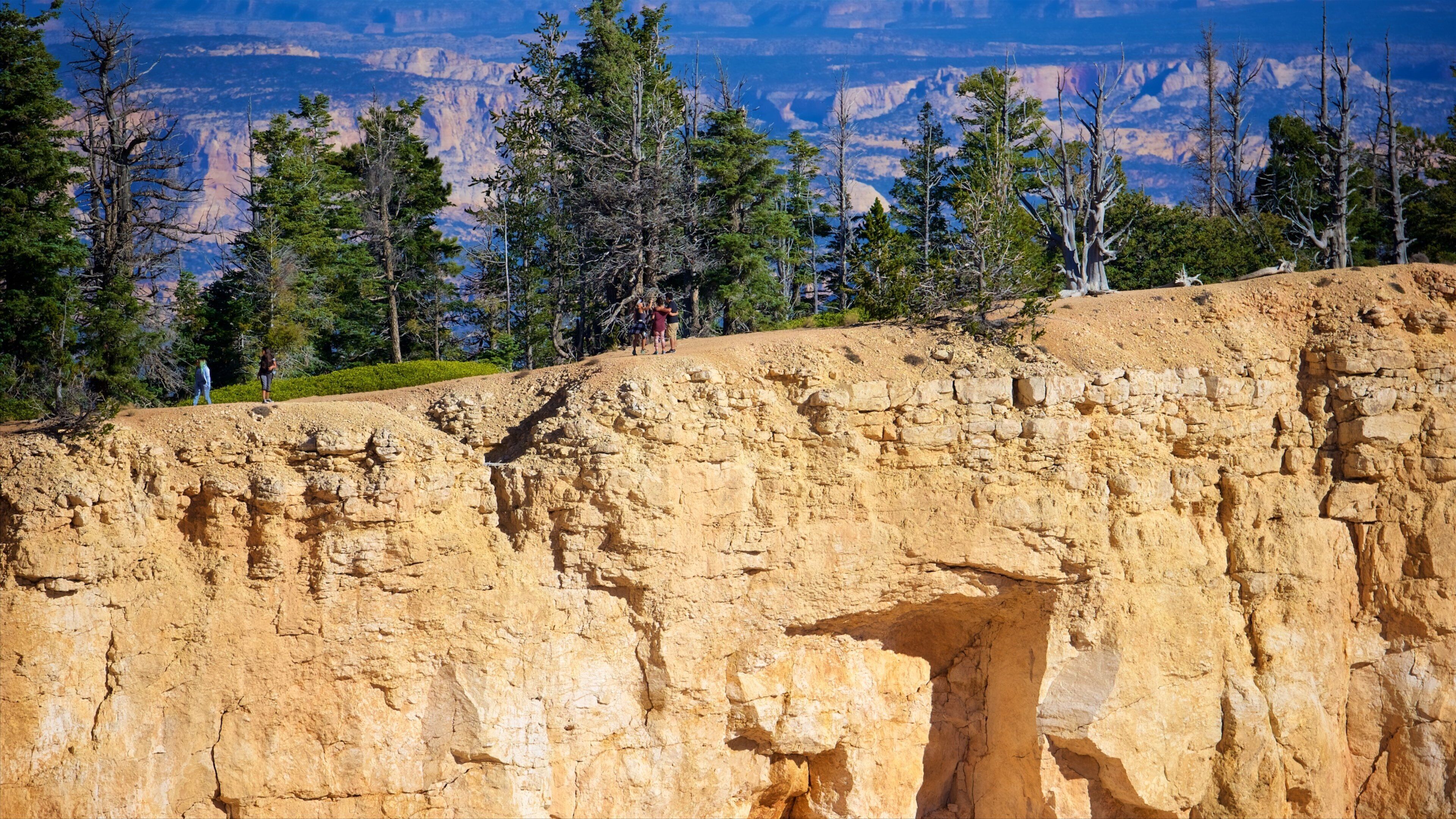 A canyon with a large rock formation and a group of people standing on a ledge.