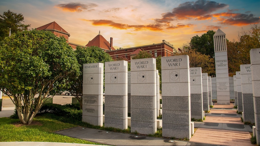 a gorgeous autumn landscape at East Tennessee Veterans Memorial in World's Fair Park with stone slabs surrounded by autumn colored trees and lush green trees and powerful clouds at sunset in Knoxville