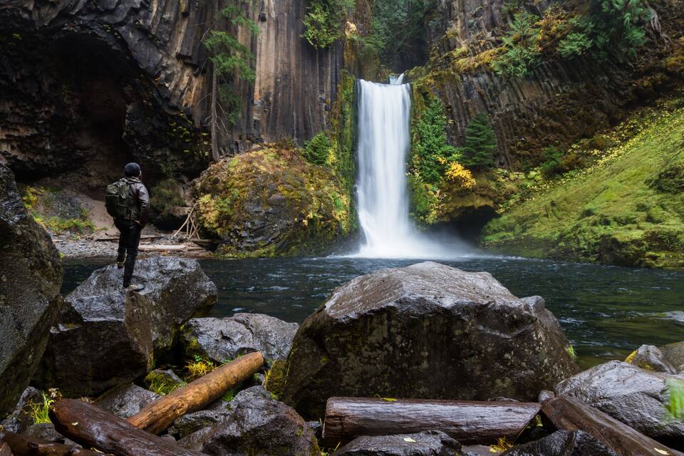 Une cascade, un terrain rocheux et une personne portant un sac à dos.
