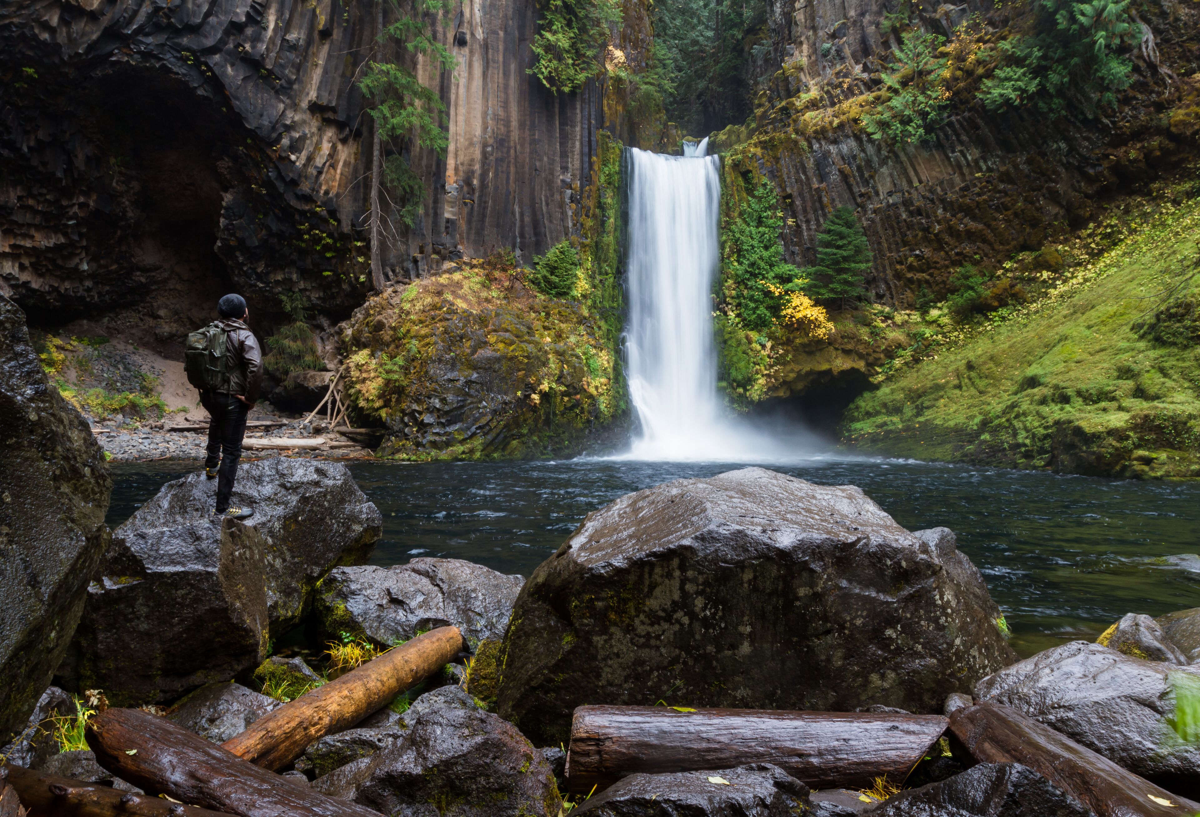 A waterfall, rocky terrain, and a person with a backpack.