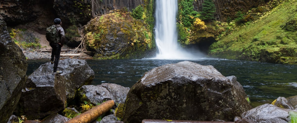 A waterfall, rocky terrain, and a person with a backpack.