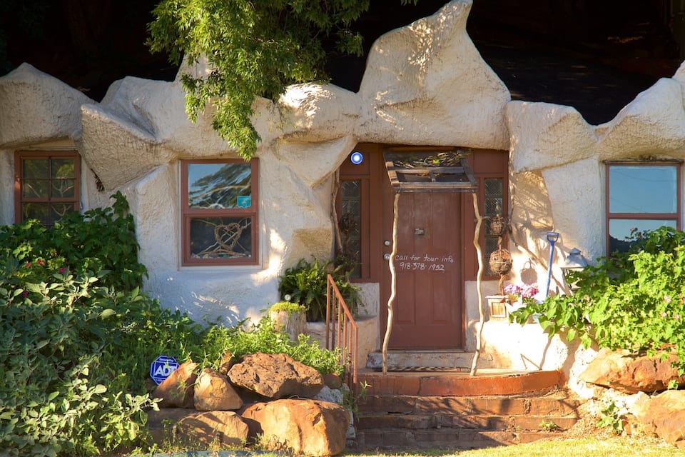 A house with a unique stone facade, a wooden door, and a small porch with steps.