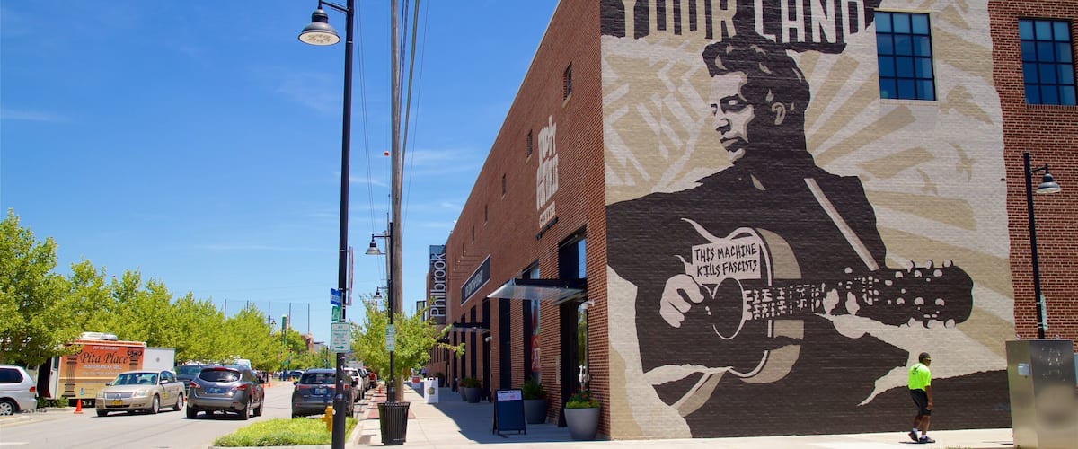 A mural on a building with a man holding a machine and a sign that says "THIS LAND IS YOUR LAND".