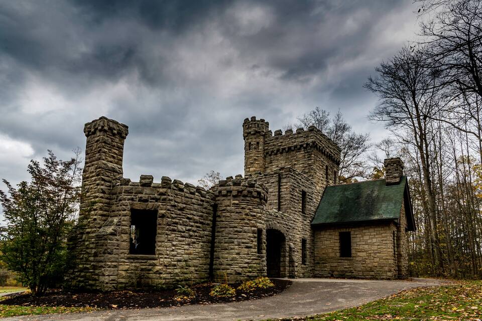 A stone castle with a turret and a small building with a green roof.
