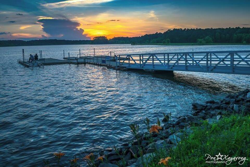 A wooden pier extending into a lake at sunset.