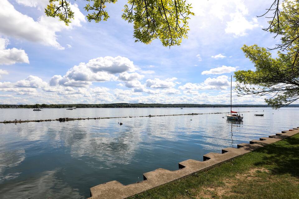 Um lago tranquilo com barcos, um cais e céu claro.