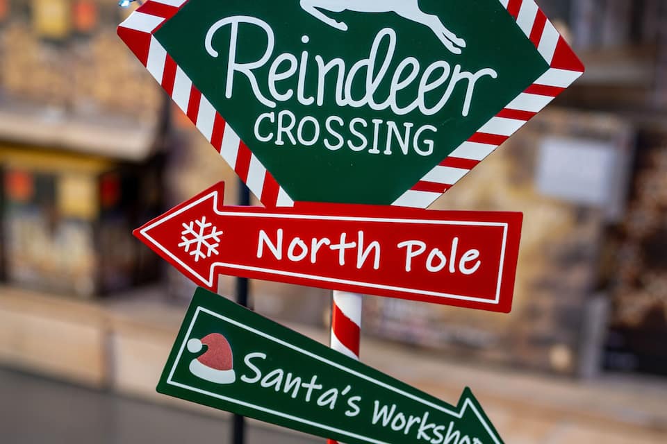 A signpost with directional arrows for 'Reindeer Crossing', 'North Pole', 'Santa's Workshop', and 'Reindeer Stables'.