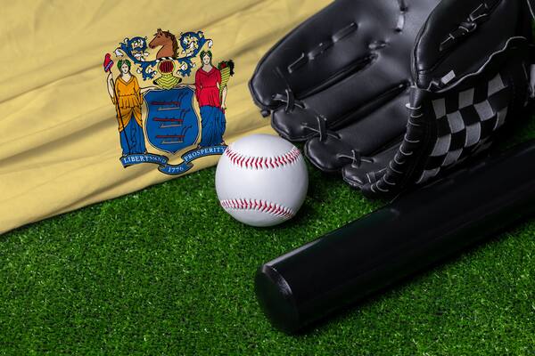 Baseball bat, glove and ball near New Jersey flag on green grass background