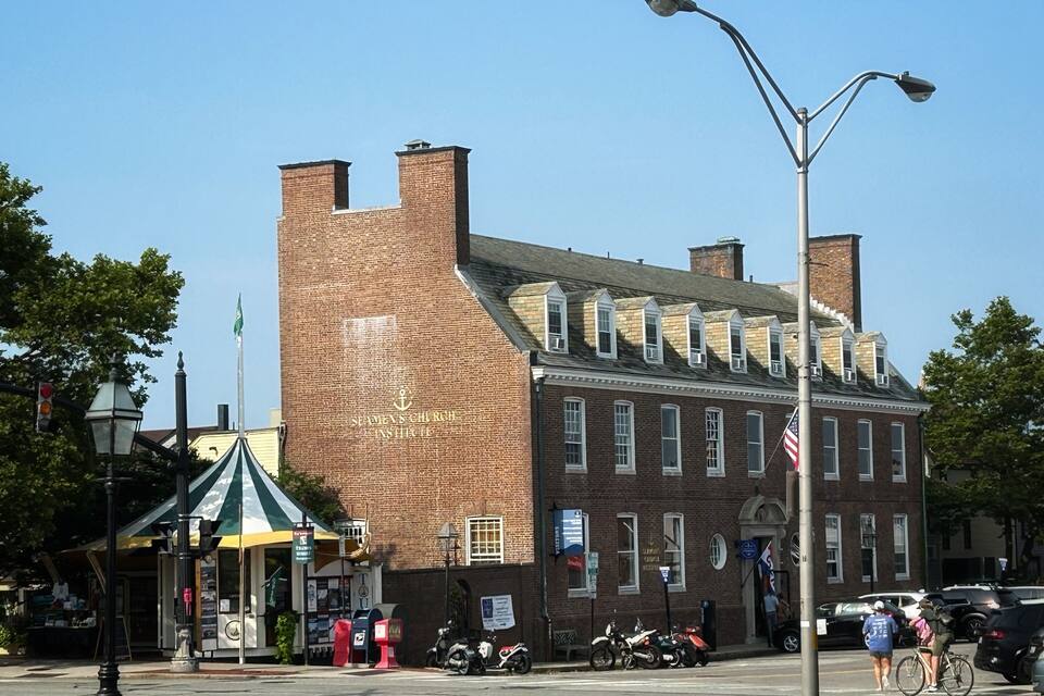 A historic brick building with a green and white awning, a street lamp, and parked motorcycles.