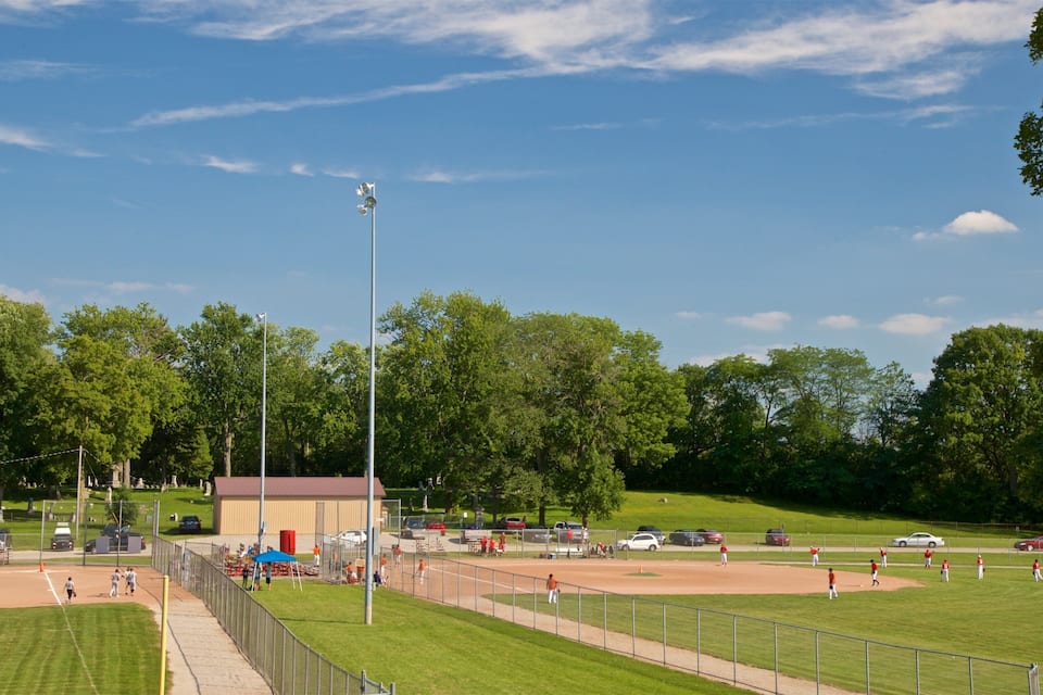 Um campo de beisebol com jogadores, um banco de reservas e um placar.