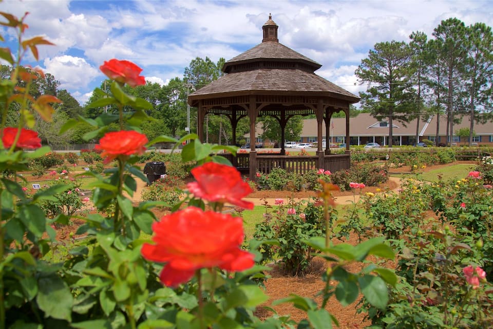 Un gazebo circondato da un giardino con fiori e alberi diversi.