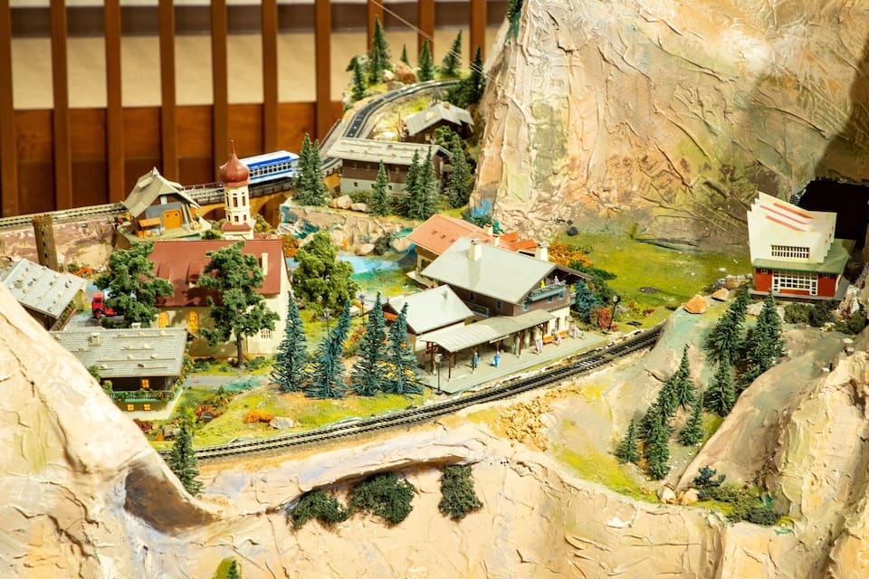 A detailed model of a mountainous town with a train track, buildings, and trees.