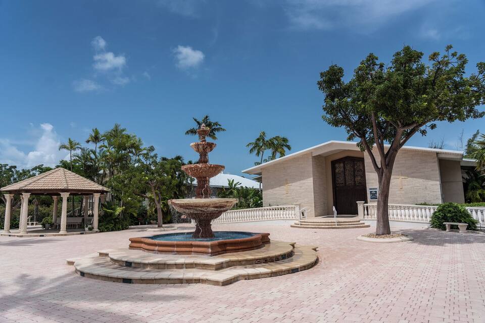 A multi-tiered fountain, a gazebo, and a building with a cross on its facade.